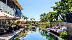 a pool at a resort with people sitting on chairs next to it at Cargo Remote Mui Ne in Phan Thiet