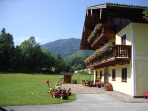 a building with a balcony with flowers on it at Pferdehof Almgut - Reiten für Kinder, Natur und Erholung nahe Salzburg in Faistenau