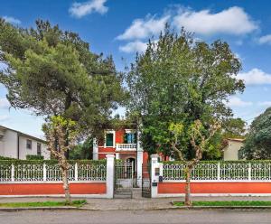 a white fence in front of a house with trees at B&B Villa Regina in Pisa