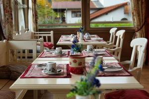 two tables in a restaurant with plates and cups on them at Landhotel Guglhupf in Schwangau