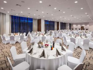 a banquet hall with white tables and white chairs at Mercure Warszawa Ursus Station in Warsaw