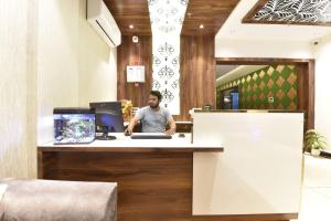 a man sitting at a desk with a computer at Hotel Shaily Royal in Kota