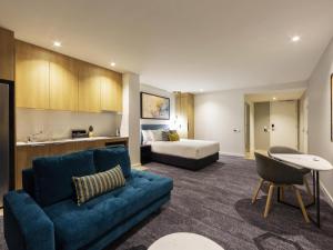 a living room with a couch and a bed at Mercure Canberra Belconnen in Canberra