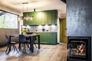 a kitchen with green cabinets and a table and a fireplace at Dom U Piepki in Zdunowice Małe
