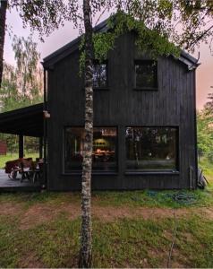 a black house with a tree in front of it at Dom U Piepki in Zdunowice Małe +14 photos