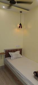 a bedroom with a white bed with a pendant light at Mukherjee Lodge in Rāmpur Hāt