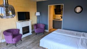 a bedroom with purple chairs and a bed and a tv at BonBon Chambre d'hôtes in Saint-Julien-de-Lampon