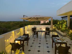 a patio with tables and chairs and an umbrella at Villa Escape In in Kuilapayam +20 photos