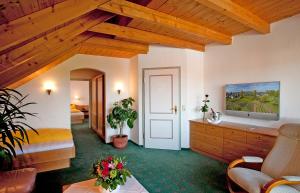 a living room with wooden ceilings and a room with a tv at Hotel-Restaurant Walserhof in Wasserburg am Bodensee