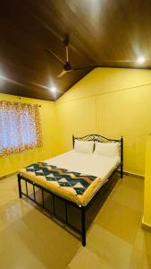 a bed in a yellow room with a ceiling at Gokarna Beach Vibes in Gokarn