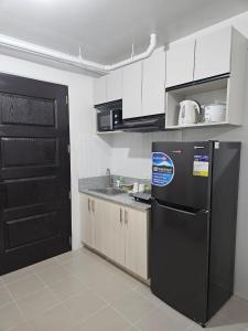 a kitchen with a black refrigerator and white cabinets at Leina Life-Style Comfy Studio Balcony near Mactan Airport in Bankal