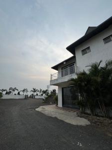 a white house with palm trees in front of it at Infinity farm and garden in Bhopal