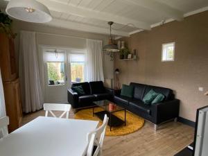 a living room with a black couch and a table at B & Buitenlust in Schagerbrug