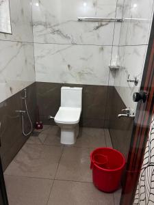 a bathroom with a white toilet and a red bucket at KOTTOOR LODGE Parakode in Adūr