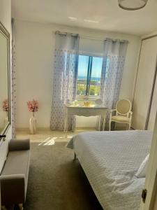 a bedroom with a bed and a table and a window at Paradise in Costa da Caparica