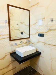 a bathroom with a white sink and a mirror at Nushi Inn in Katunayaka