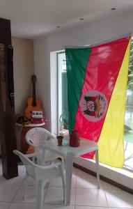 a flag is hanging in a room with a table and chairs at Hospedagem do TCHÊ in Vila Velha