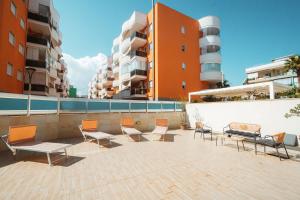 a group of chairs and tables on a patio with buildings at Velaria Boutique Apartment in Monopoli
