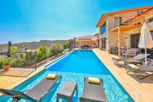 a swimming pool with chairs and a house at Patara breeze in Kaş