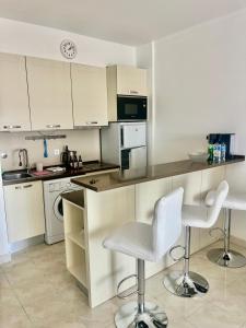 a kitchen with white cabinets and white chairs in it at Paradise in Costa da Caparica