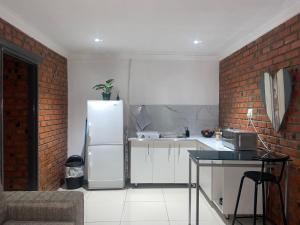 a kitchen with a white refrigerator and a brick wall at Kubbe Comfort Corner in Bloemfontein