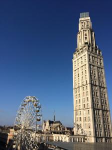 un grand bâtiment blanc avec une roue ferris devant lui dans l'établissement Le 360 TOUR PERRET 19eme PANORAMA 4 ETOILES, à Amiens