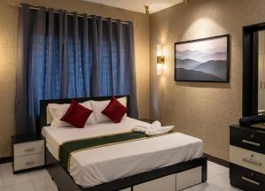 a bedroom with a bed with red pillows at Skylora Heights Inn in Kozhikode