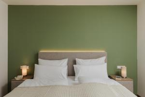 a bed with white pillows and a green wall at LÆKE Apartments - Lindau am Bodensee in Lindau