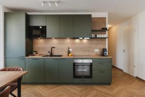 a kitchen with green cabinets and a wooden floor at LÆKE Apartments - Lindau am Bodensee in Lindau +29 photos