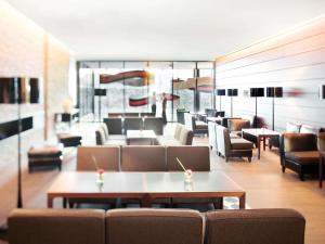 a living room with a couch and tables and chairs at MÖVENPICK Hotel Stuttgart Airport in Leinfelden-Echterdingen