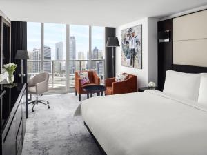 a hotel room with a bed and a desk and chairs at Mövenpick Hotel Jumeirah Lakes Towers Dubai in Dubai