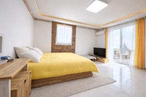 a bedroom with a yellow bed and a television at Danyang paramaeul in Danyang