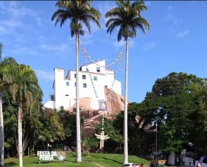 a building on top of a mountain with palm trees at Hospedagem do TCHÊ in Vila Velha