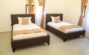 two beds sitting next to each other in a room at Topaz Apartments Shanzu in Mombasa