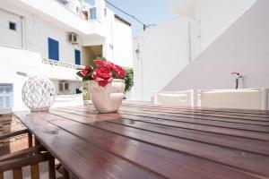 a vase with flowers on a wooden table on a balcony at Naxian Harmony 300m from the beach in Naxos Chora