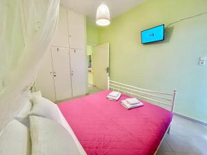 a bedroom with a pink bed with a tv on the wall at ZEN, Oneiropagida, Aegina in Vathí