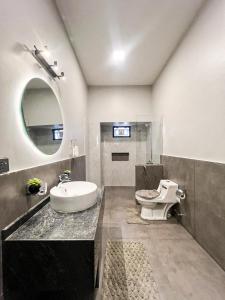 a bathroom with a sink and a toilet and a mirror at Ghumo - 10BR Villa in Bahadurabad near Aga Khan in Karachi +43 photos