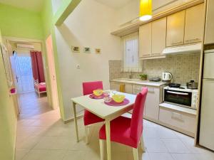 a kitchen with a small table and red chairs at ZEN, Oneiropagida, Aegina in Vathí