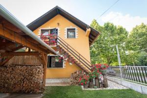 a small yellow house with flowers in a yard at Kovács Vendégház in Harkány