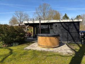 a building with a wooden barrel in a yard at Bungalow Doris with Hot Tub | 4 persons in Gasselte