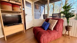 a living room with a red chair and a tv at Bungalow Doris with Hot Tub | 4 persons in Gasselte