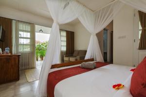 a bedroom with a large white bed with curtains at Abipraya Ubud in Ubud