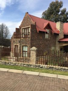 a brick house with a fence at Windsor House in Dullstroom