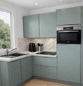 a kitchen with blue cabinets and a sink and a window at Le refuge Marin - Mer, Piscine, tennis & Loisirs à 2 pas in Cabourg