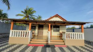 a small white house with a porch and palm trees at Sea shells on the seashore in Cocoanut Island