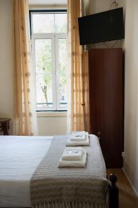 a bedroom with a bed with two towels on it at Corações Unidos "A Pensão" in Alcobaça