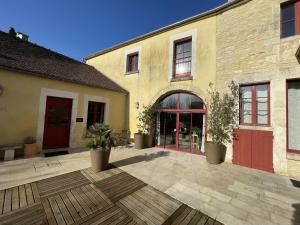 a building with red doors and a wooden patio at Le P'tit Louis in Saint-Cyr-les-Colons