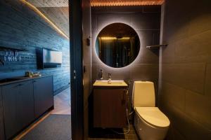a bathroom with a sink and a toilet and a mirror at Arctic Lumo Resort in Kuusamo