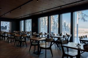 a restaurant with tables and chairs and large windows at Arctic Lumo Resort in Kuusamo