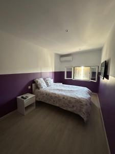 a bedroom with a bed and a purple wall at Appartement Bellegarde in Bellegarde